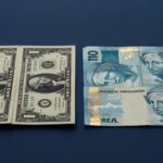 Notas de dólar americano e real brasileiro lado a lado representando a relação cambial entre as moedas