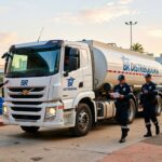 Caminhão-tanque branco da BR Distribuidora cercado por quatro policiais uniformizados em operação de fiscalização combustíveis