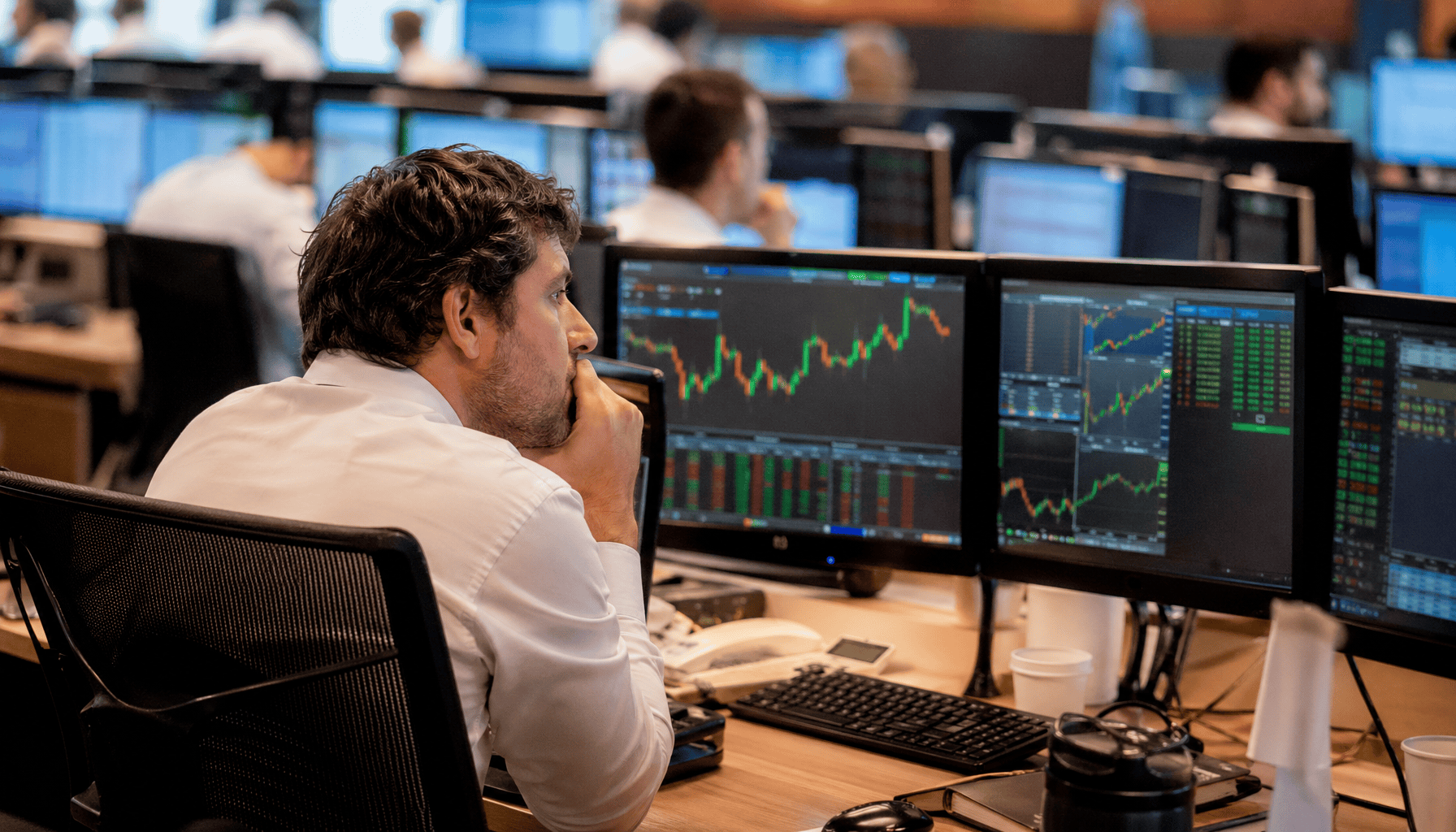 Trader concentrado observando múltiplos monitores com gráficos financeiros e cotações em tempo real no pregão